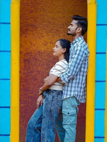 A stylish pose against a colorful, striped wall. Their casual outfits and the vibrant background create a modern and trendy pre-wedding photo.