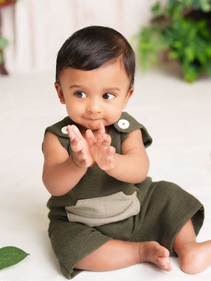 A handsome little man clapping his hands during his sitter session. His joyful expression and the simple, natural setup keep all the focus on him.