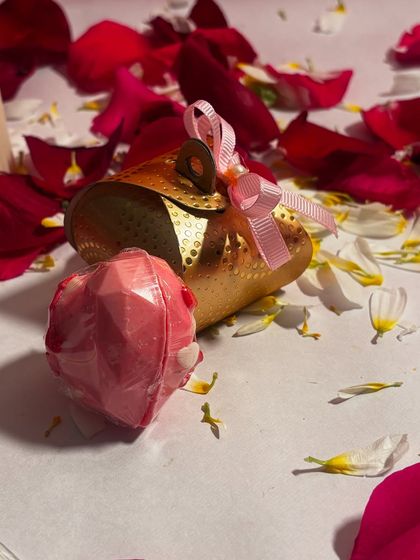 A closer look at the handmade heart shaped chocolate bomb, presented alongside its golden gift pouch. It's a perfect little treat to gift someone special.