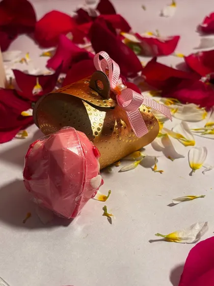 A closer look at the handmade heart shaped chocolate bomb, presented alongside its golden gift pouch. It's a perfect little treat to gift someone special.