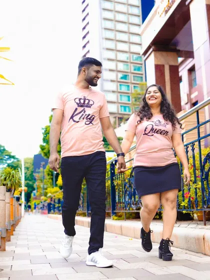 A happy, carefree walk down a city sidewalk. The couple's matching "King" and "Queen" t-shirts show off their fun personalities.