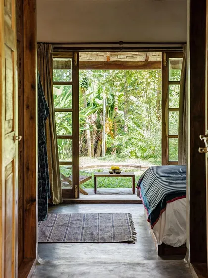 Looking from the Garden Room's bedroom out to its private veranda and garden. The large doors create a seamless transition between the indoor and outdoor spaces.