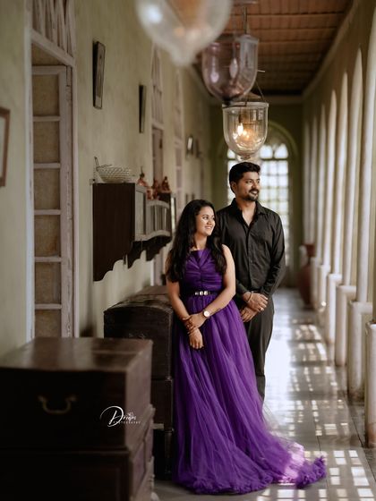 A beautifully lit pre-wedding photo in a long corridor. The purple gown adds a rich pop of color to the vintage-inspired setting.