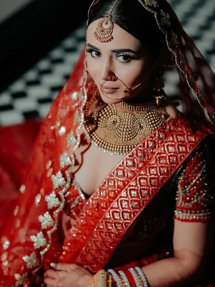 A powerful close-up of the bride, her hand partially covering her face, highlighting her stunning eye makeup and jewelry.