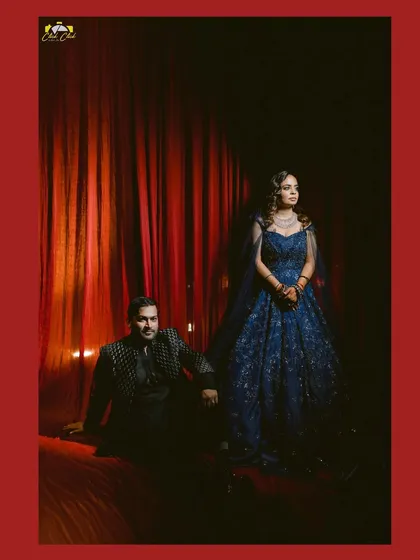 A regal portrait of the couple against the rich, red backdrop of their sangeet decor.