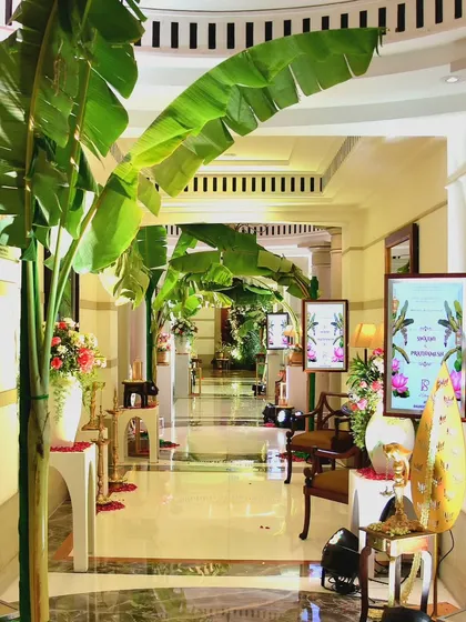 A hallway transformed into a tropical oasis with an archway of banana leaves, leading guests towards the main ceremony area.