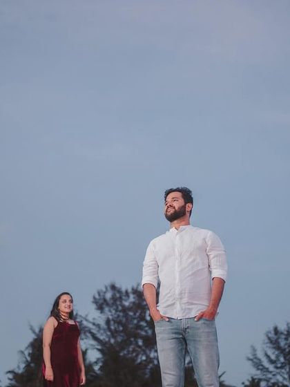 An artistic, wide-angle shot that uses negative space to create a cinematic and thoughtful portrait of the couple on the beach.
