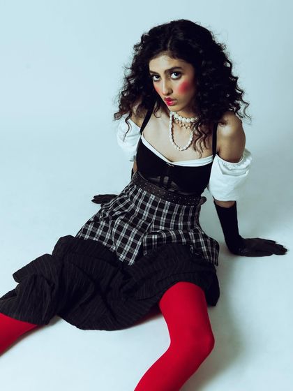 A creative and conceptual portrait with a vintage doll-like aesthetic. The styling, with its plaid skirt, puffed sleeves, and bright red tights, is highly theatrical. My job was to create a mood and composition that felt both playful and slightly unsettling.