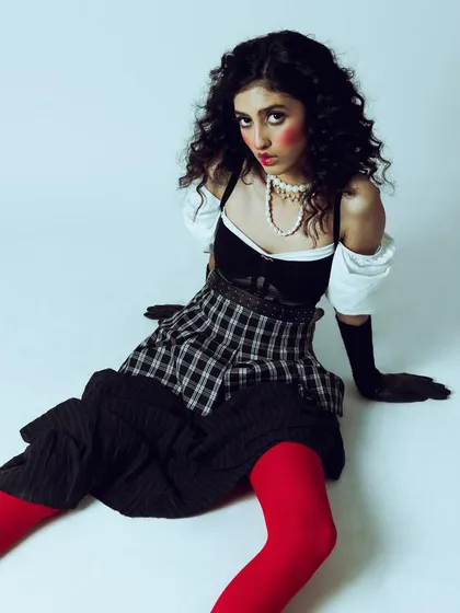 A creative and conceptual portrait with a vintage doll-like aesthetic. The styling, with its plaid skirt, puffed sleeves, and bright red tights, is highly theatrical. My job was to create a mood and composition that felt both playful and slightly unsettling.
