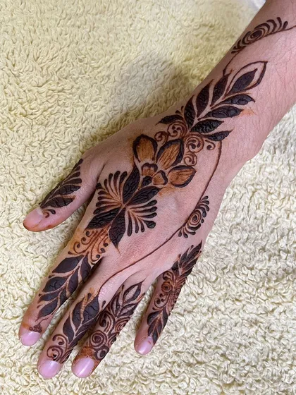 A bold Arabic style design with large, shaded leaves and flowers. The pattern flows diagonally across the hand for a striking effect.