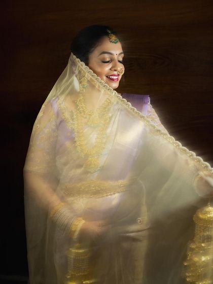 An ethereal portrait of the bride, Amruta, her face gently covered by her veil, smiling in anticipation of the ceremony.
