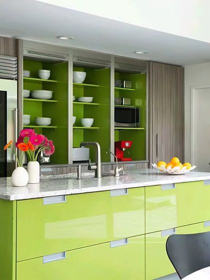 This kitchen design makes a statement with a bright lime green island and cabinets. The vibrant color is paired with wood-textured units and a large, modern refrigerator, creating a fun and energetic heart of the home.