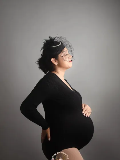 Sometimes, a simple and classic portrait is the most powerful. Using a minimalist backdrop and a simple black bodysuit, we can create a striking image that focuses entirely on the beautiful silhouette of your pregnancy. It's modern, artistic, and timeless.