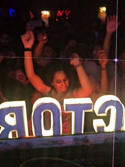 A partygoer dancing behind the club's logo at Sugar Factory. The energy is palpable from every corner of the room.