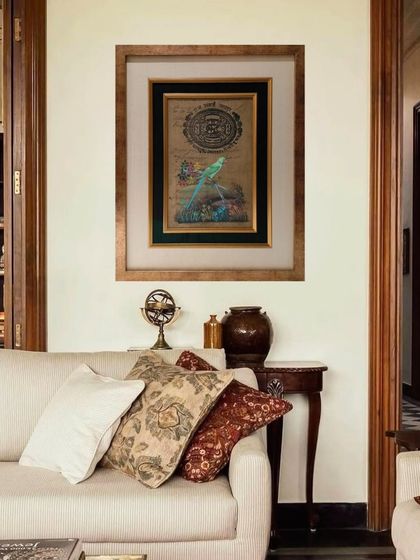 The framed antique document becomes a sophisticated focal point above a sofa. The framing elevates the object from a simple paper to a piece of art with presence and spatial authority.