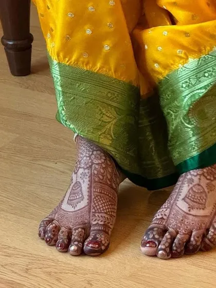 This bridal foot mehendi features classic jhumki (bell) motifs, perfectly complementing the bride's traditional attire and anklets.
