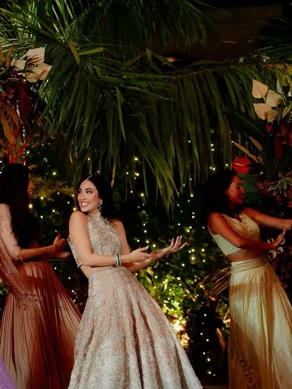 The bride and her bridesmaids perform against a backdrop of tropical foliage and warm lights.