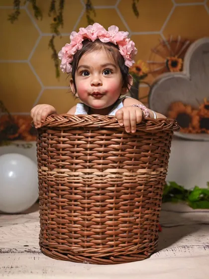 A playful shot of the baby popping out of a wicker basket. This prop is part of our rustic sunflower theme and adds a charming touch to the photoshoot.