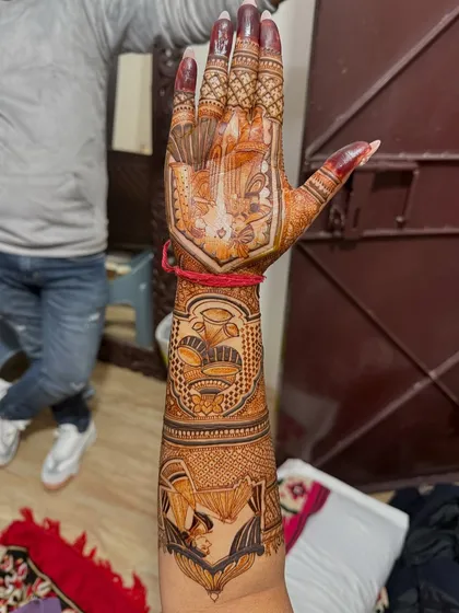 A full arm bridal design seen from the back of the hand. This view shows how the story continues all the way around the arm, with scenes like the bride in her doli and other wedding rituals.