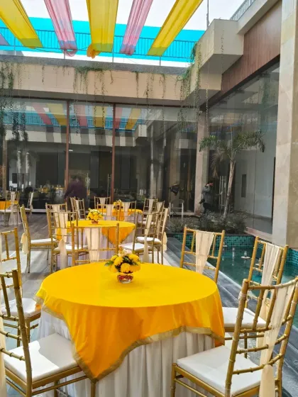 A simple yet elegant seating arrangement for a Haldi lunch. The tables are covered with bright yellow cloths, and the open-air setting by a water body adds a refreshing touch.