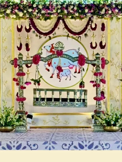 This is a traditional naming ceremony I designed with a Lord Krishna theme. The setup includes a decorated cradle, a pichwai-style backdrop featuring cows, and floral arrangements with marigolds and tuberoses for a culturally rich celebration.