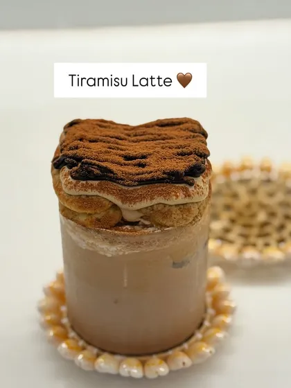 A detailed look at the Tiramisu Latte, with its distinct layers of coffee-soaked biscuit and creamy topping, dusted with cocoa powder.