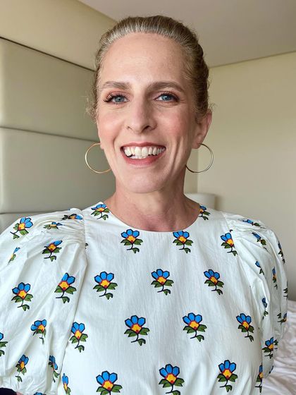A full-length view of the daytime look. The makeup is minimal and fresh, with a top knot hairstyle that is both stylish and practical.