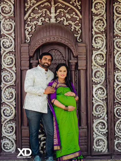 A full-length portrait of a couple in traditional attire, framed by a grand, antique-style door.