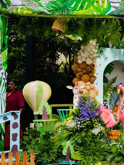 A vibrant and colorful corner of Eshaan's safari party, featuring a mix of jungle foliage, pink flamingos, a hot air balloon, and other animal figures.