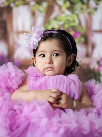 A close-up portrait of a baby girl in a fluffy purple dress. We focus on capturing their expressions and beautiful eyes.