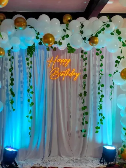 A full, straight-on shot of the jungle-themed birthday setup. The combination of white balloons and gold chrome accents adds a touch of elegance to the playful theme.