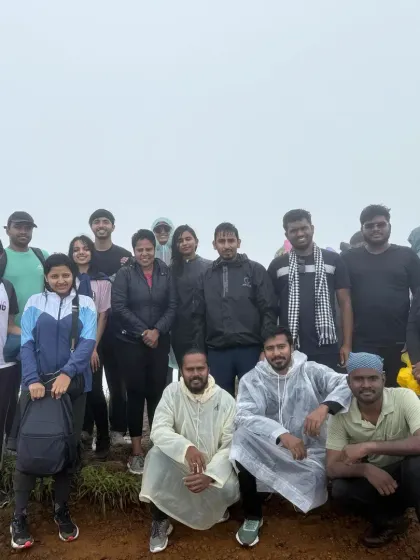 A group of trekkers at a summit, some in ponchos, ready for the unpredictable mountain weather.