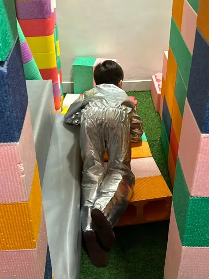 An astronaut exploring a maze of soft play blocks. Our play area encourages imaginative adventures.