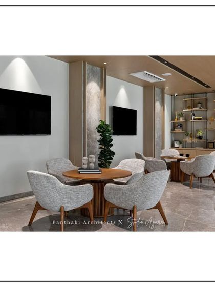 This client lounge offers multiple seating arrangements to accommodate different group sizes. The design uses a neutral palette with wood accents and built-in shelving to create a space that is both professional and comfortable.