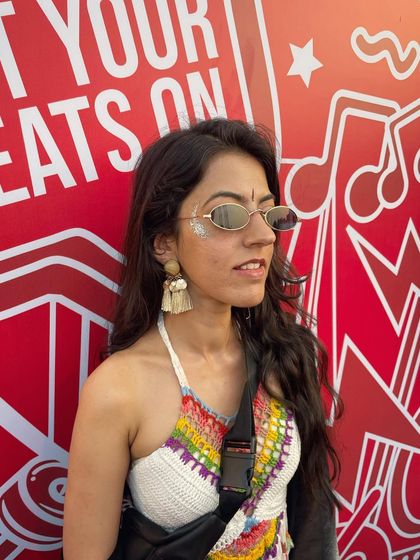 A subtle silver glitter design on the cheekbone of a client with a cool, bohemian festival outfit.