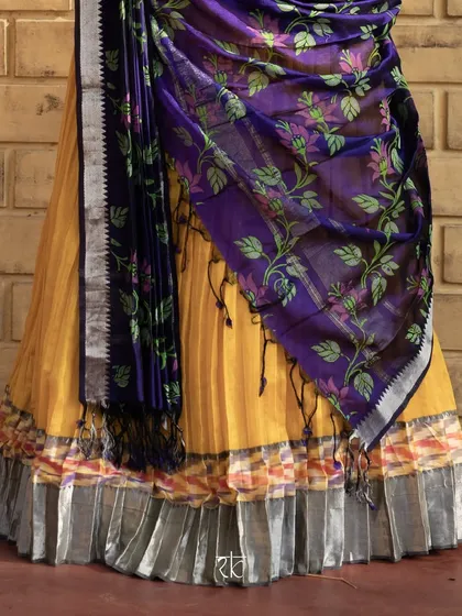 The lower half of the mustard and navy blue ensemble, showing the beautiful drape of the floral dupatta over the pleated skirt.