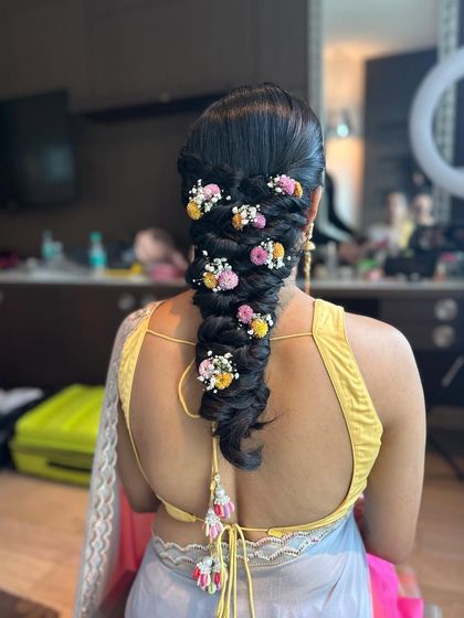 A close-up of the messy braid with multi-colored flowers, a vibrant and festive choice for a haldi or mehndi.