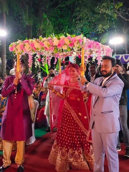 A bride in a stunning red lehenga enters under a pink floral Phoolon ki Chadar. It’s a beautiful tradition and a photo opportunity you don't want to miss.