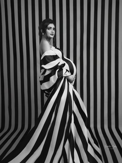 Bold lines and a powerful gaze. The combination of the striped gown and matching backdrop creates a visually stunning, almost optical effect. This is a portrait for the fearless, fashion-loving mother.