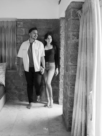 A classic black and white shot of the couple walking hand-in-hand indoors. The monochrome tones add a timeless and artistic quality to the moment.