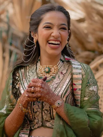 A candid shot of the bride with her hair in a half-updo with curls, accessorized with a delicate pearl hair chain.