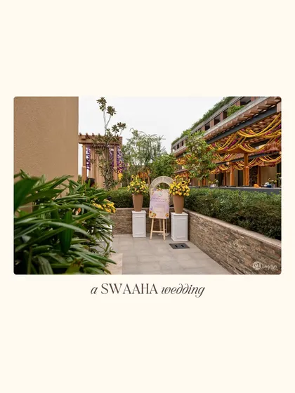 A wide view of a vibrant outdoor pre-wedding event, with a welcome sign and colorful floral arrangements leading the way.