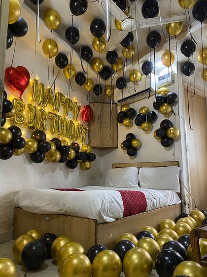 Another angle of the black and gold setup, showing the density of the ceiling balloons and the small balloon clusters on the wall.