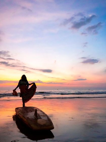 A beautiful silhouette of a woman on a surfboard against a pastel sunset. This shot uses negative space to create a sense of peace, freedom, and elegance.