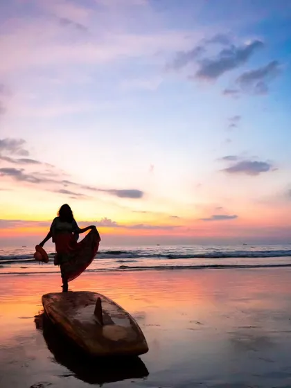 A beautiful silhouette of a woman on a surfboard against a pastel sunset. This shot uses negative space to create a sense of peace, freedom, and elegance.