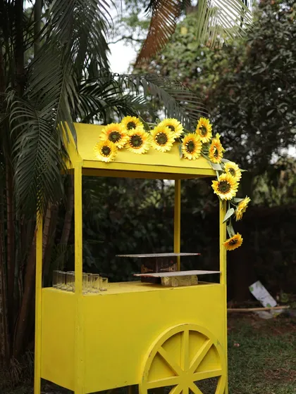 A charming yellow cart adorned with sunflowers, designed as a drink or food station for the Haldi ceremony. Thematic details like this enhance the guest experience.