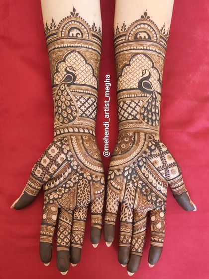 A bold and beautiful design centered around peacock figures within traditional archways, covering the hands in rich, dark henna.