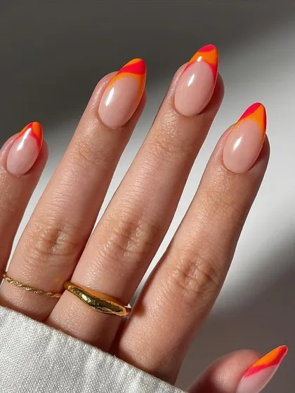 Another view of the stunning sunset-inspired French manicure. This angle highlights the clean lines and vibrant colors of the layered orange and red tips on the elegant almond shape.