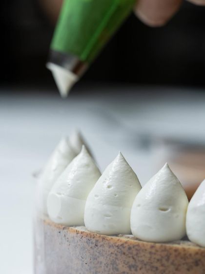 The art of piping. Here, a chef demonstrates how to create perfect, uniform peaks of meringue on a cake.