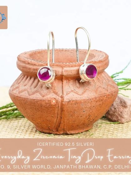 A pair of tiny drop earrings with a rich, ruby-colored zirconia stone. These add a touch of warmth and color to any outfit.